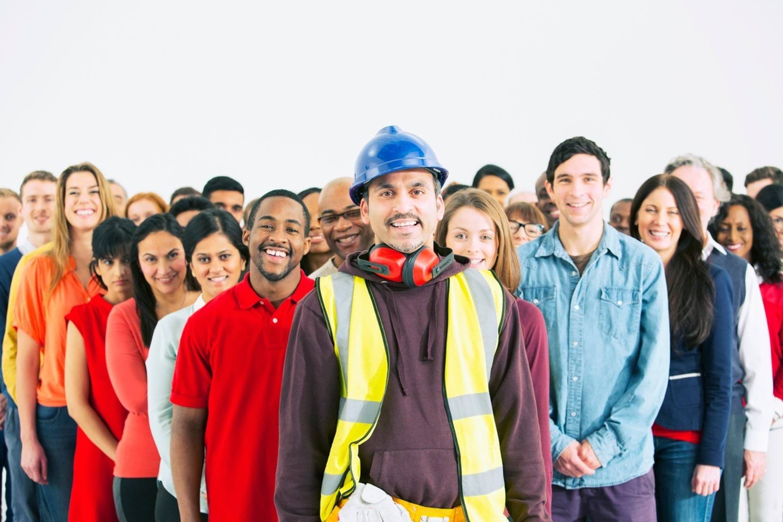 Group of workers from all backgrounds standing together with the lead person being a construction worker